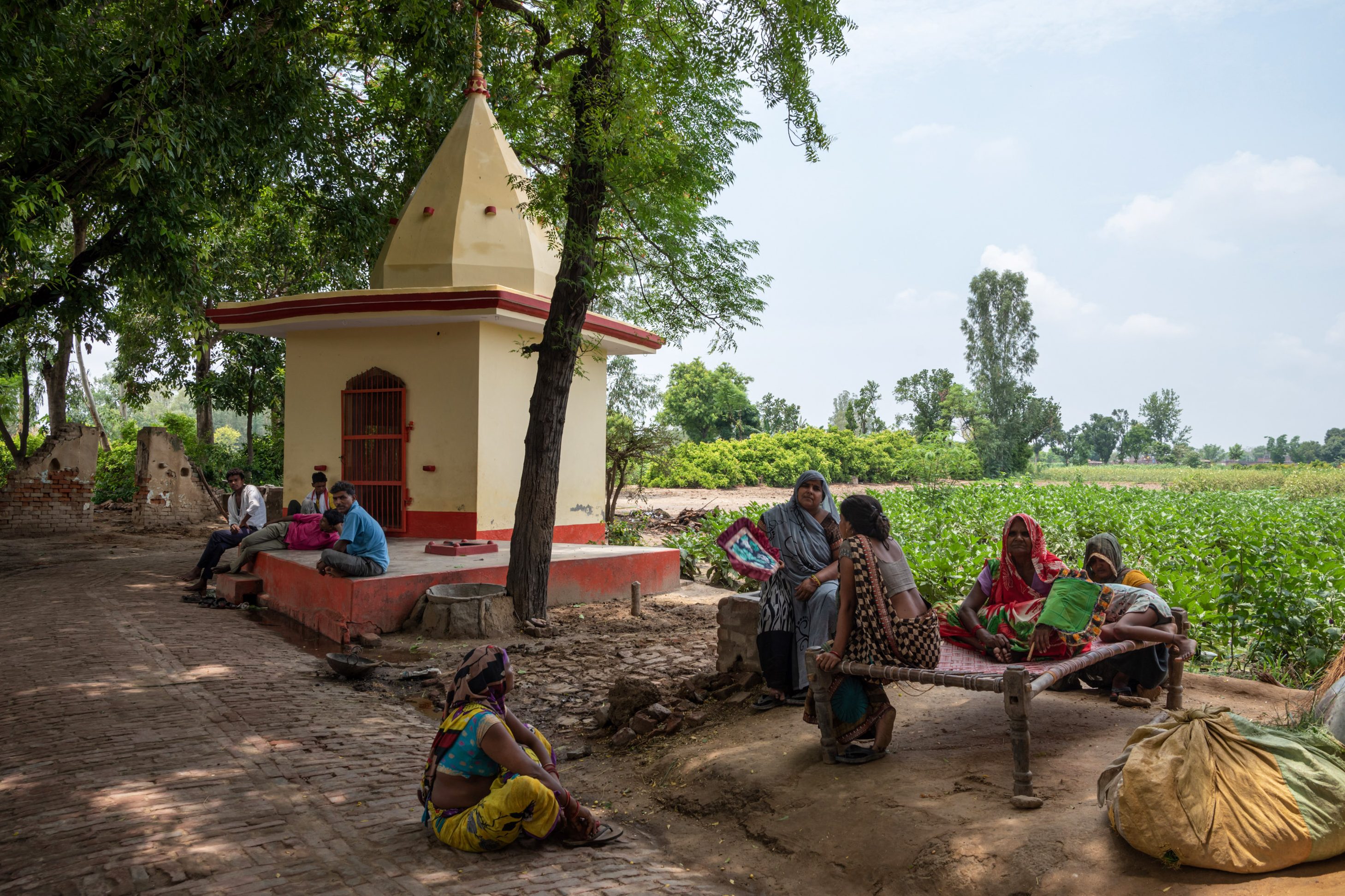 مردم برای فرار از گرما زیر یک درخت بنیان کنار معبد می نشینند.