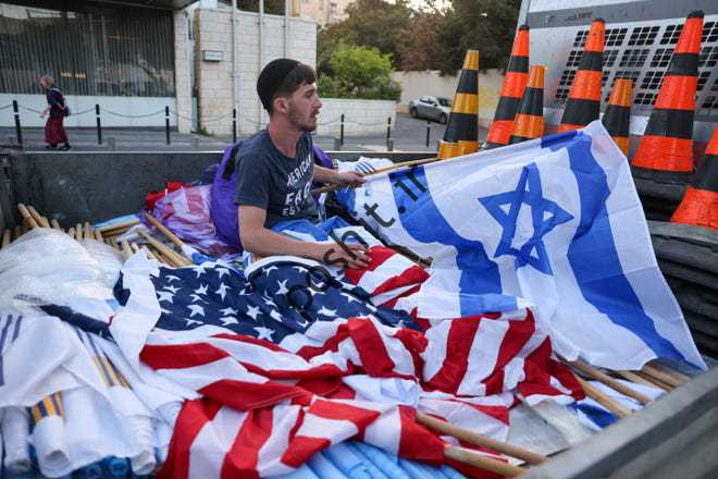 یک کارگر پرچم ملی اسرائیل و ایالات متحده را در 12 ژوئیه 2022 در اورشلیم و پیش از سفر فردا جو بایدن رئیس جمهور ایالات متحده به اسرائیل آماده می کند.